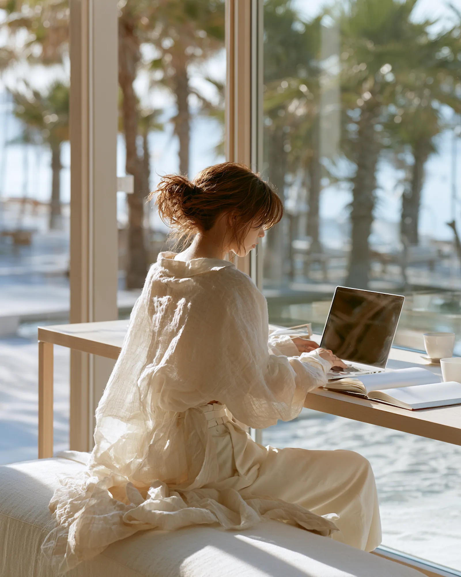 自然光の中、PCに向かって思考する女性の後ろ姿。MOREARIAが大切にする想いを象徴するイメージ